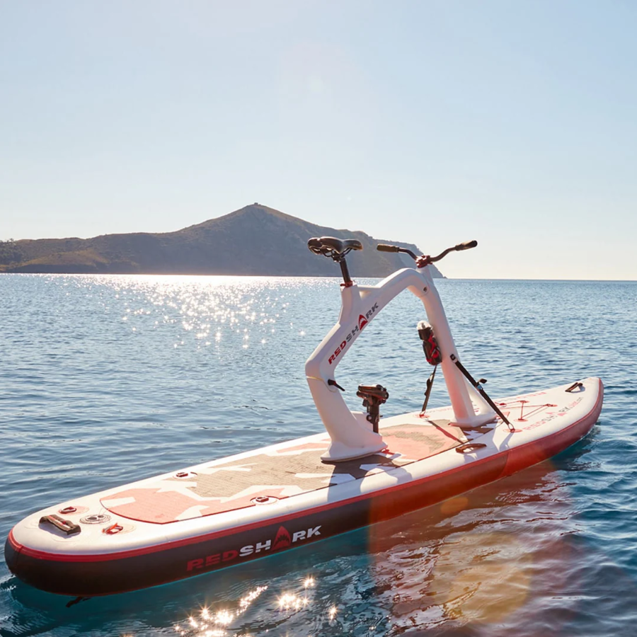 Red Shark Enjoy Bike Surf on calm sea with mountain views in the distance.