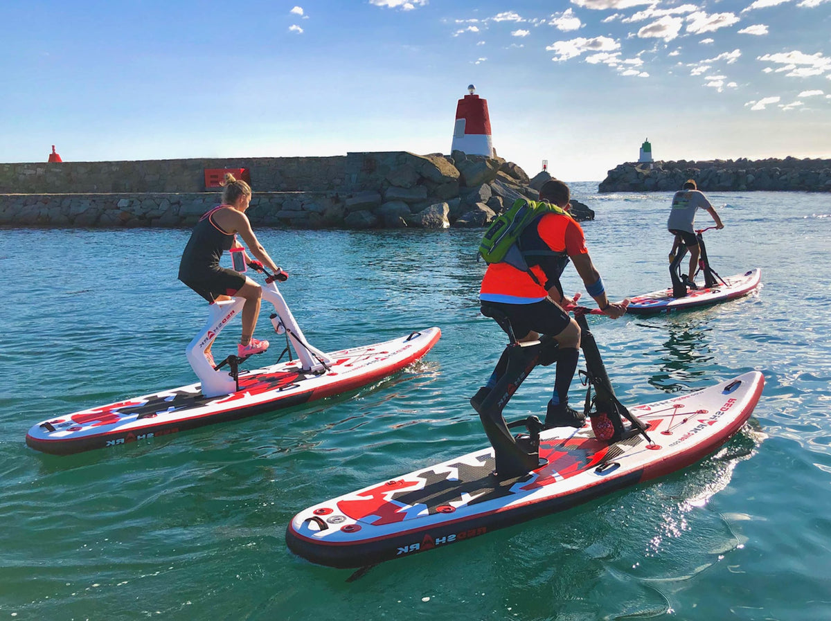 Group enjoying a sunny day on Red Shark Enjoy Bike Surfs by the harbor entrance with lighthouses.