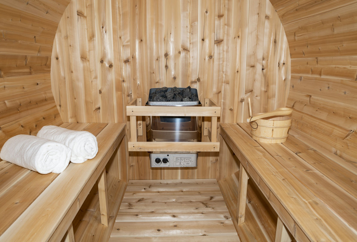 Interior view of Leisurecraft Canadian Timber Outdoor Barrel Sauna, with a focus on its benches and electric heater.