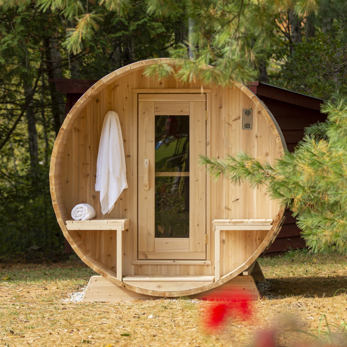 Front view of Leisurecraft Canadian Timber Outdoor Barrel Sauna in an outdoor setting surrounded by forest.