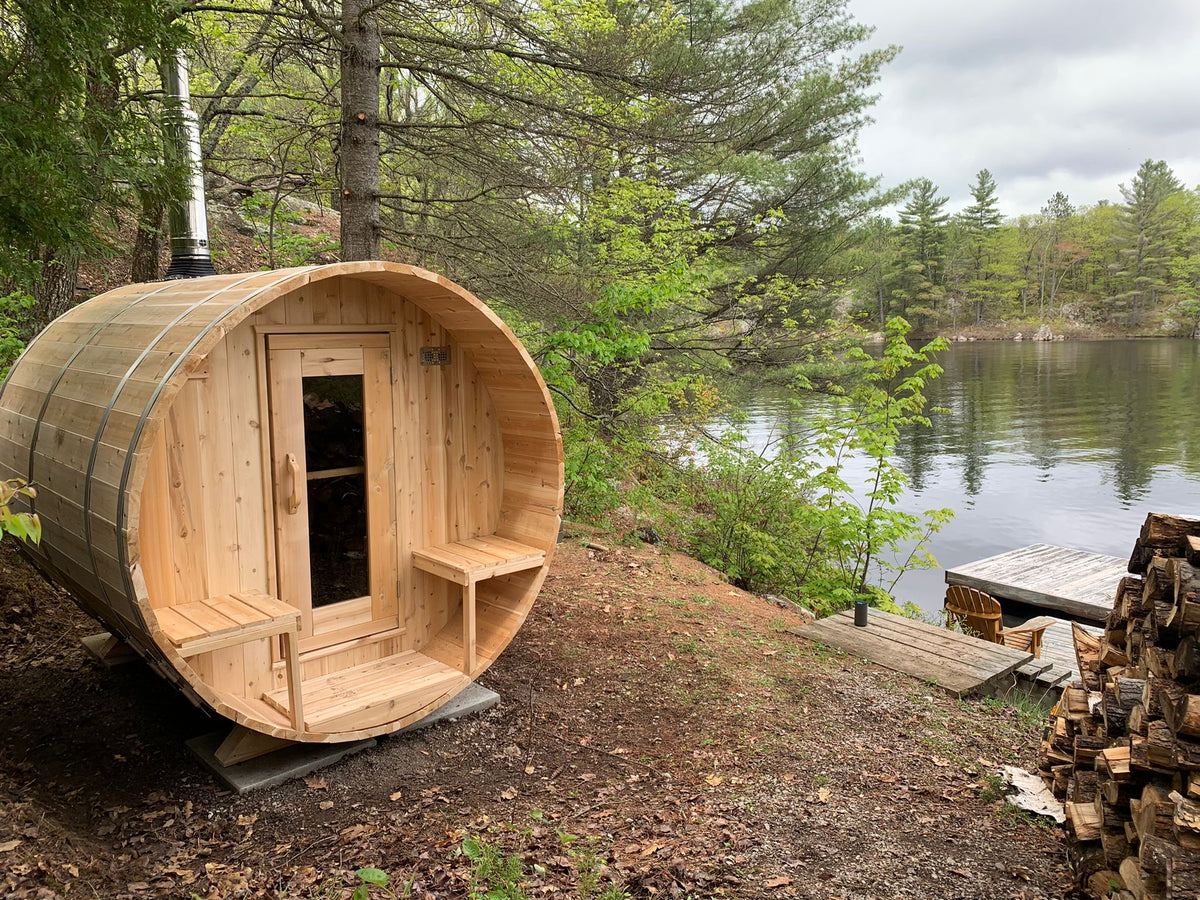 Leisurecraft Canadian Timber Outdoor Barrel Sauna in an outdoor setting with a lake in the background.