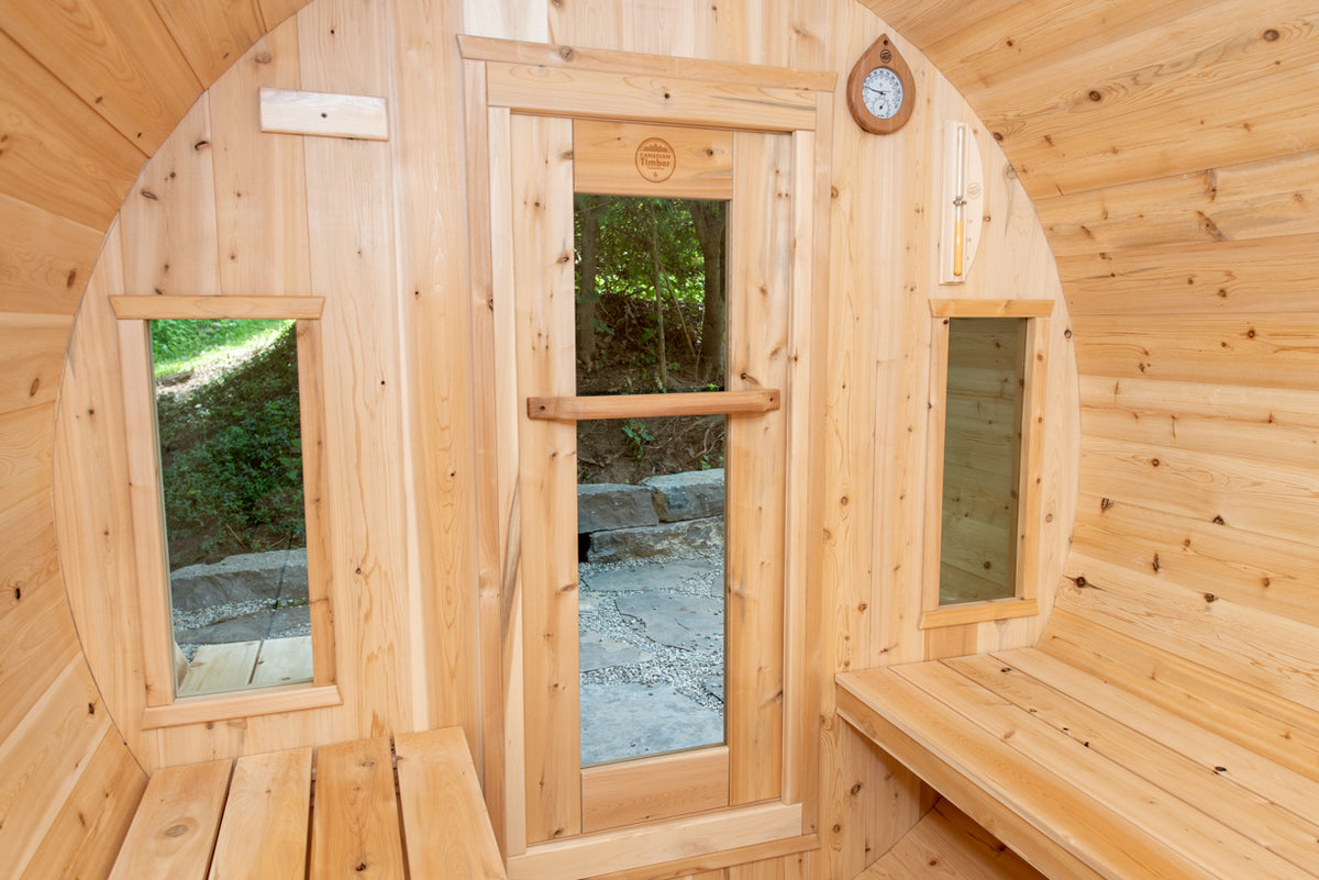 Interior view of Leisurecraft Canadian Timber Tranquility Outdoor Barrel Sauna, showing its two windows and its tempered glass door.