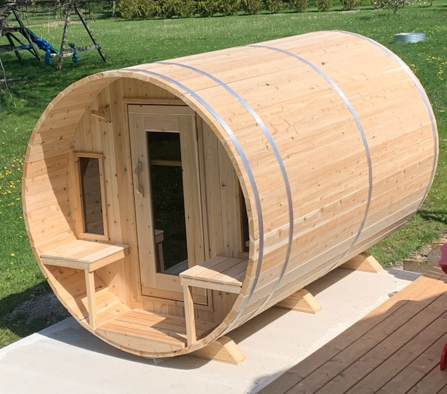 Side view of a Leisurecraft Canadian Timber Tranquility Outdoor Barrel Sauna in a garden during a sunny day.