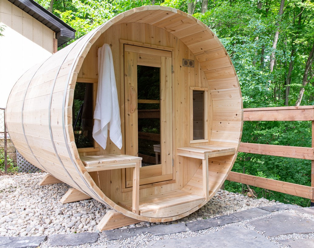 Diagonal view of Leisurecraft Canadian Timber Tranquility Outdoor Barrel Sauna in an outdoor setting surrounded by nature.