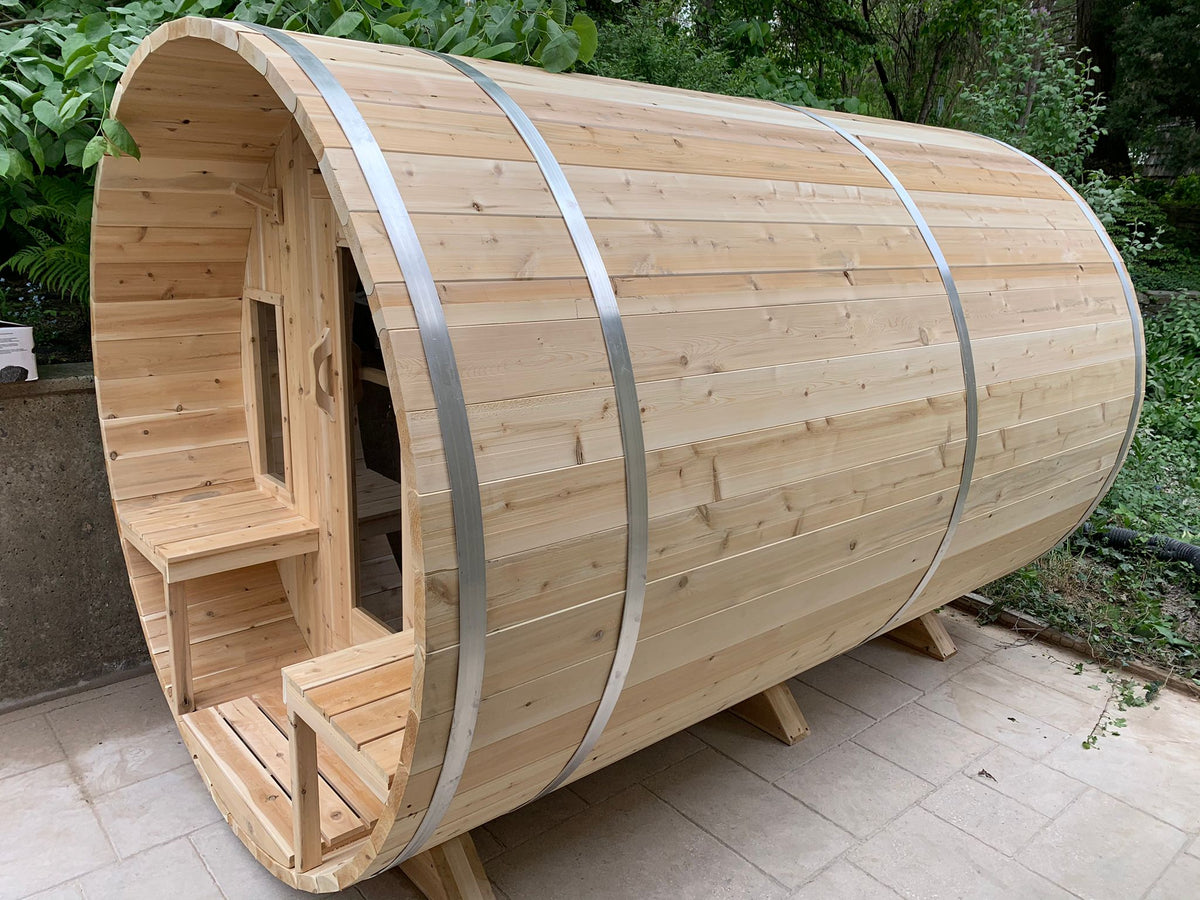 Side view of Leisurecraft Canadian Timber Tranquility Outdoor Barrel Sauna in an outdoor setting with a forest on the background.