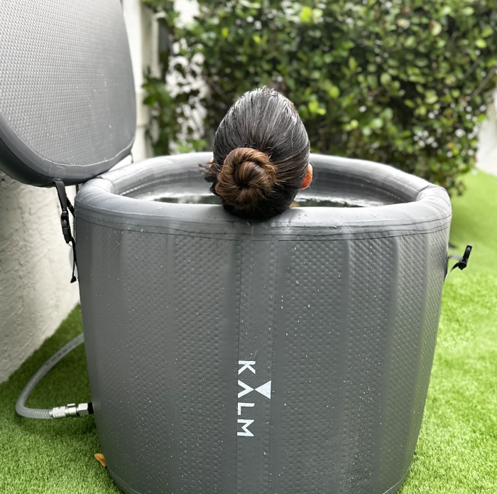 Woman using a Kalm Inflatable Cold Plunge Gray version in an outdoor setting.