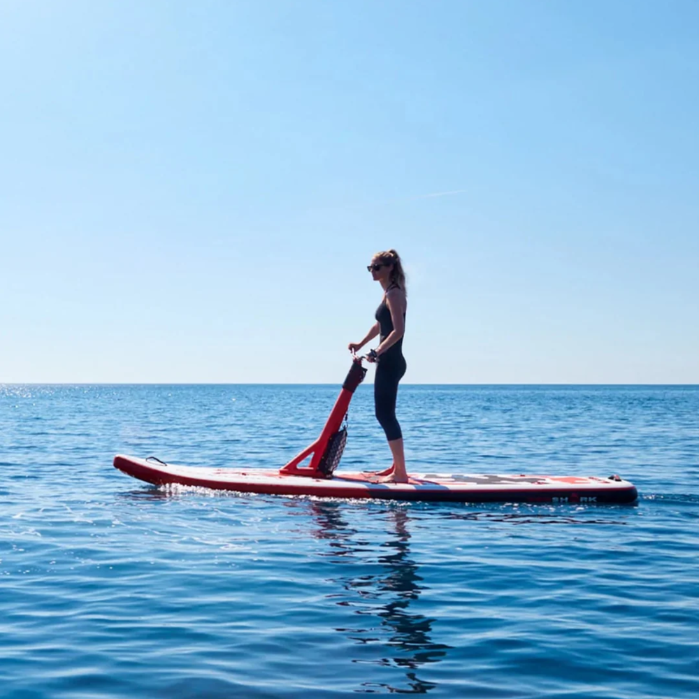 Woman riding a Red Shark Scooter Bike Surf on a calm sea with clear sky.