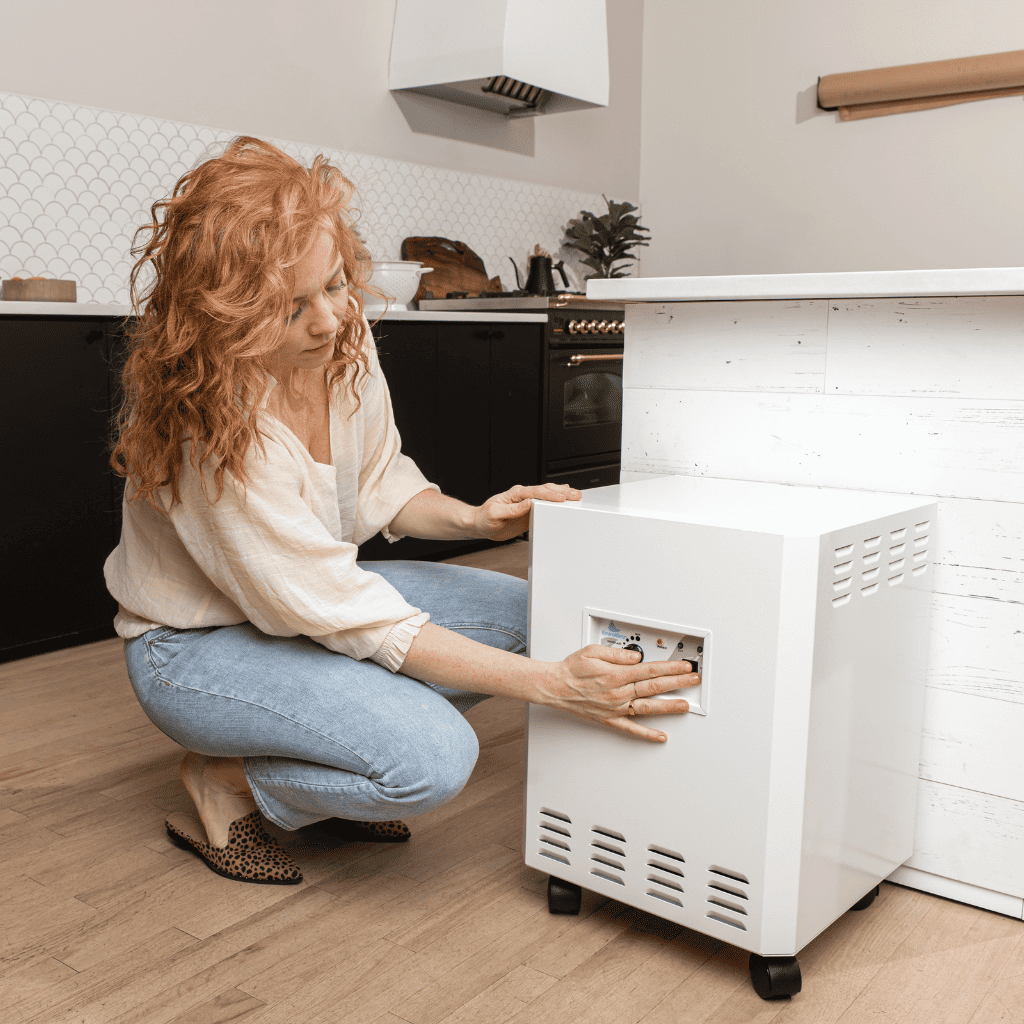 Woman adjustating the EnviroKlenz Air System Plus in a modern kitchen, illustrating ease of use and maintenance.